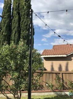 the back yard is fenced off with string lights and trees in front of it