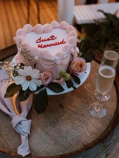 a heart shaped cake on a table with flowers and wine glasses in front of it