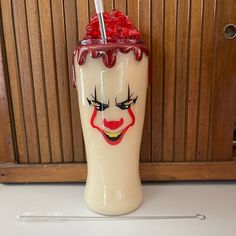 a ceramic cup with a straw in the shape of a clown's face on it