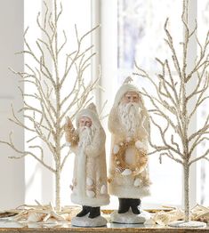 two santa claus figurines sitting on top of a table