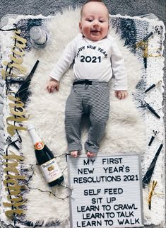 a baby laying on top of a sign next to a bottle