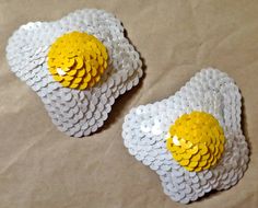 two yellow and white brooches on brown paper