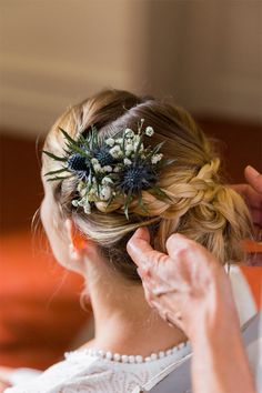 a woman is getting her hair done with flowers