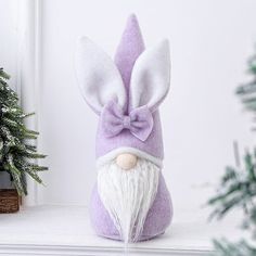 a purple and white stuffed animal with a bow on it's head next to a christmas tree