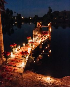 a person sitting on a dock with candles and flowers