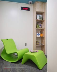 a green chair sitting next to a book shelf