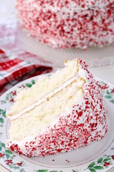 a slice of cake with white frosting and red sprinkles on a plate