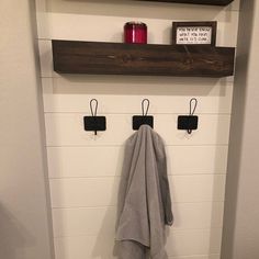 a bathroom with a towel rack and two hooks on the wall next to a toilet