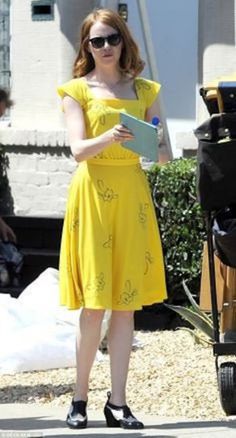 a woman in a yellow dress holding a book