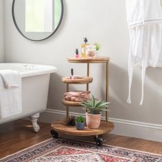 a bath tub sitting next to a white sink under a mirror on top of a wooden shelf