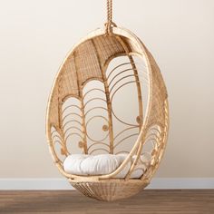 a rattan hanging chair with white pillows