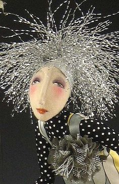 a doll is dressed in black and white polka dots with silver hair, sitting on a table