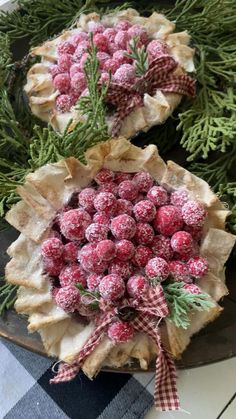 two pies decorated with berries and pine cones