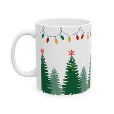 a white coffee mug with christmas lights on the trees and snowflakes hanging from it