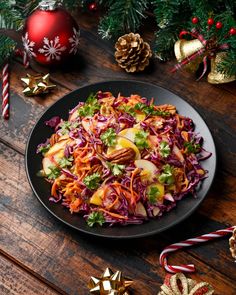 a plate of coleslaw with apples, carrots and christmas decorations on the table