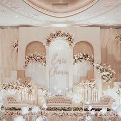 an elaborately decorated stage set up for a wedding reception with white flowers and greenery