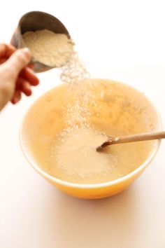 a person is sprinkling sugar into a bowl with a spoon on the table