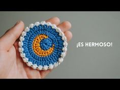 a hand holding a crocheted brooch with the words, fes hermoso