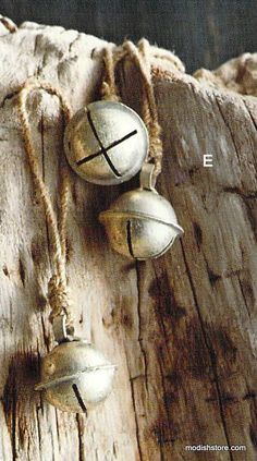 three bells hanging from a wooden post on the side of a tree trunk with rope