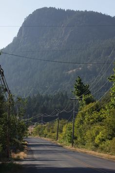 an empty street with power lines and mountains in the background