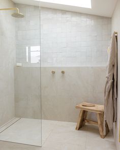 a walk in shower sitting next to a wooden bench under a skylight on top of a tiled floor