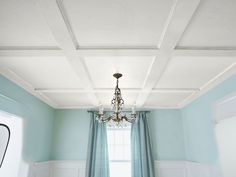 a chandelier hanging from the ceiling in a room with blue walls and curtains