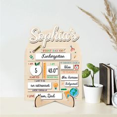 a wooden sign that says sepia's first day of school on it next to a potted plant