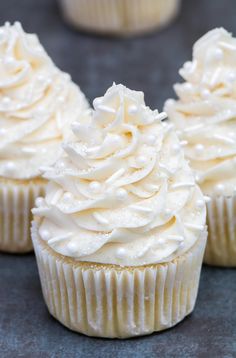 three cupcakes with white frosting sitting on top of each other in rows