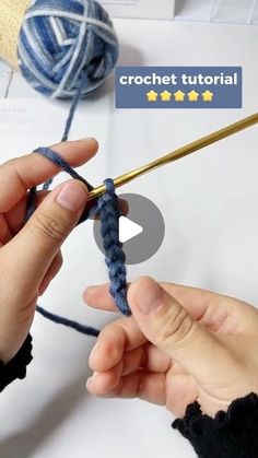 two hands are knitting yarn together with crochet needles and an object in the background