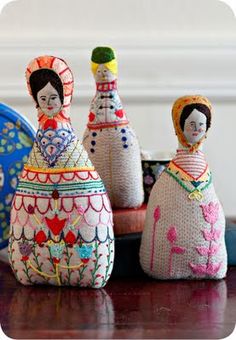 three decorative dolls sitting on top of a wooden table