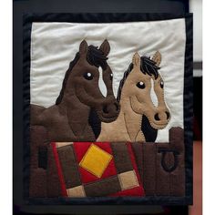 two brown horses standing next to each other on a white wall hanging with black border