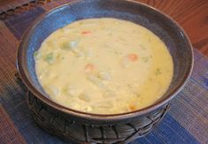 a bowl filled with soup sitting on top of a wooden table next to a blue place mat