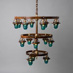 a chandelier hanging from a metal chain with blue glass shades on the bottom