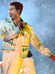 a male in a yellow shirt and white pants on stage with his hands out to the side