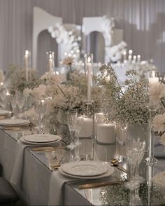 a long table with white flowers and candles is set for a formal dinner or party