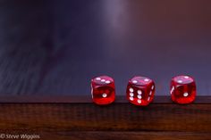 three red dices sitting on top of a wooden table next to eachother