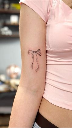 a woman's arm with a tattoo on it that has a bow in the middle