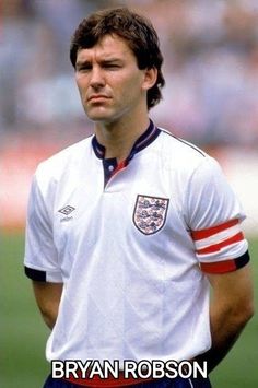 a man standing on top of a soccer field wearing a white shirt and blue shorts