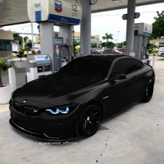 a black car parked in front of a gas station with blue lights on it's hood