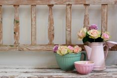 three vases with flowers in them sitting on a table next to a wooden bench