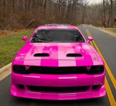 a pink car is parked on the side of the road in front of some trees