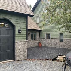 an outside view of a house with two garage doors and a deck in the front yard