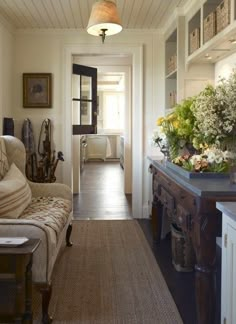 a living room filled with furniture and lots of flowers on top of a table next to a doorway