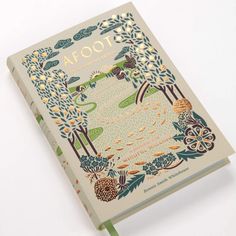 the front cover of a book with an image of trees and flowers on it, sitting on a white surface