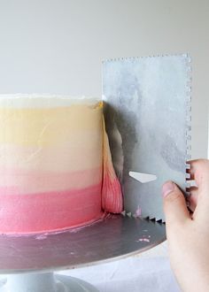 a person cutting into a cake with a knife on a plate next to the cake