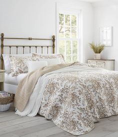 a bedroom with white walls and wooden flooring, an iron headboard and bedding