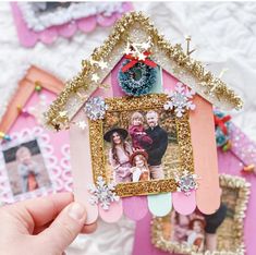 a person holding up a small house with pictures on it