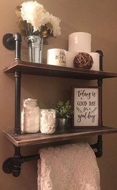 two shelves with towels, candles and flowers on them in a small bathroom area next to a toilet