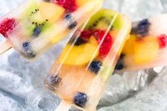 two popsicles filled with fruit on top of ice