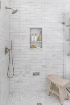 a walk in shower sitting next to a white tiled wall with shelves on the side